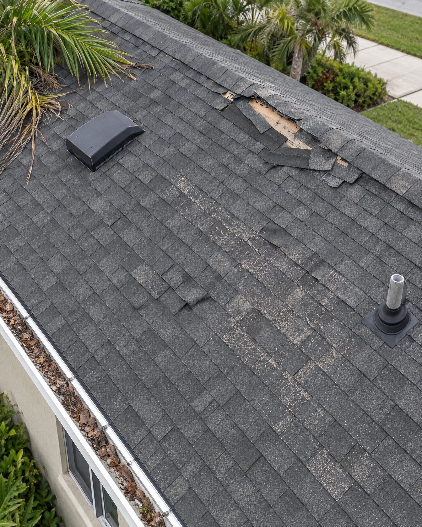 Close aerial view of storm-damaged roof shingles